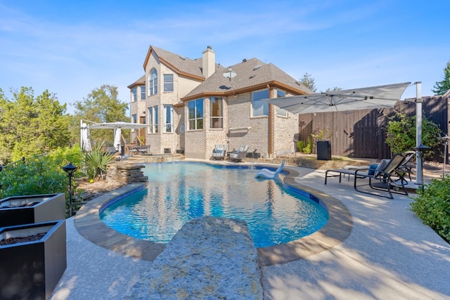 view of pool with pool water feature, a pergola, and a patio