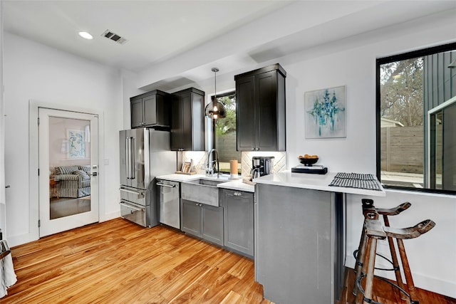 kitchen featuring pendant lighting, a wealth of natural light, stainless steel appliances, and a breakfast bar