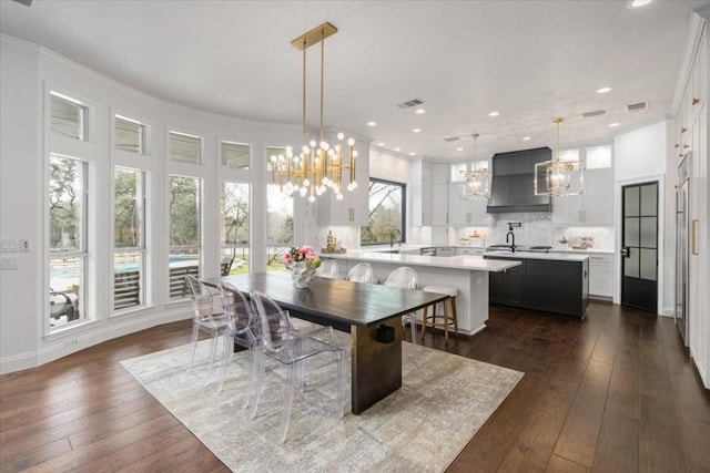 dining room with dark hardwood / wood-style flooring, ornamental molding, sink, and a chandelier