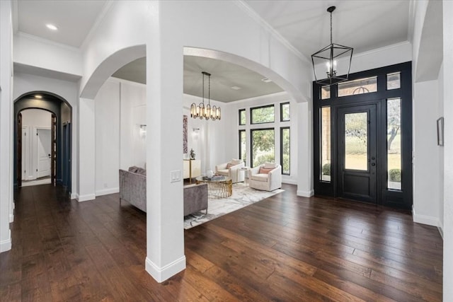 foyer with crown molding, dark hardwood / wood-style floors, and an inviting chandelier