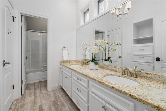 bathroom with vanity, hardwood / wood-style floors, and shower / bath combination with glass door