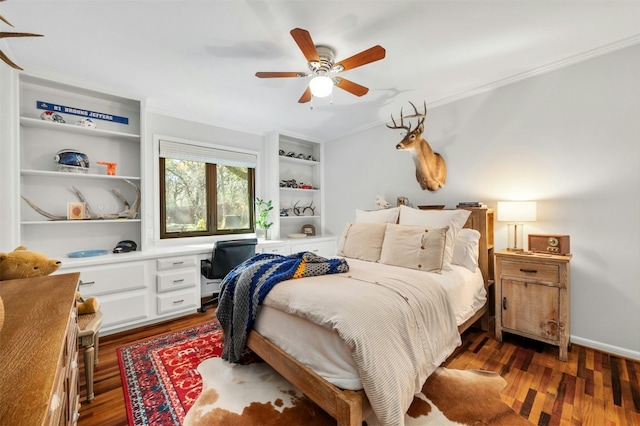 bedroom featuring dark wood-type flooring, ceiling fan, crown molding, and built in desk