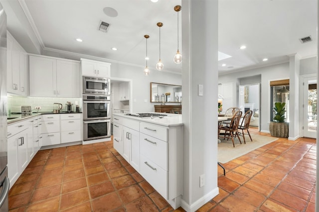 kitchen with pendant lighting, backsplash, stainless steel appliances, and white cabinets