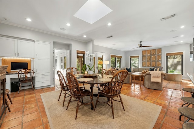 dining space with ornamental molding, built in desk, ceiling fan, and a skylight