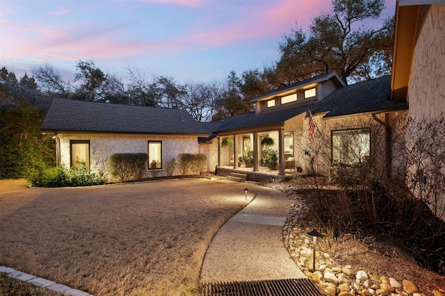 view of front facade featuring stone siding and a shingled roof