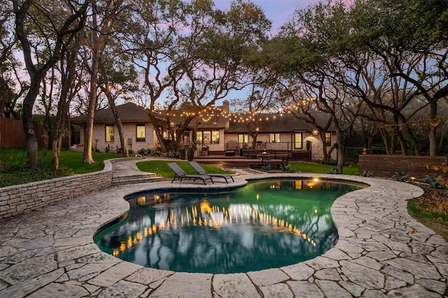 pool at dusk featuring a deck and a patio