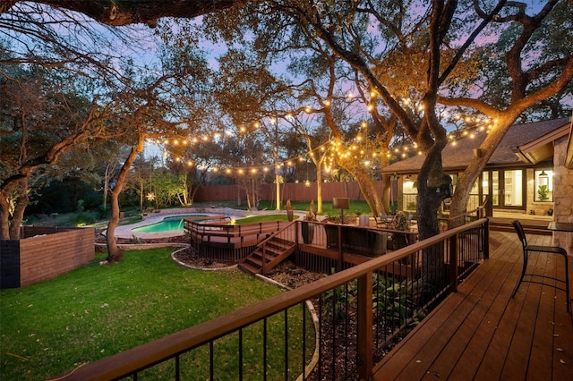 deck at dusk with a yard and a fenced in pool