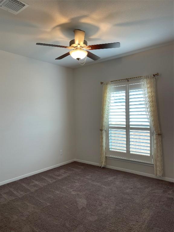 spare room with ceiling fan and dark colored carpet