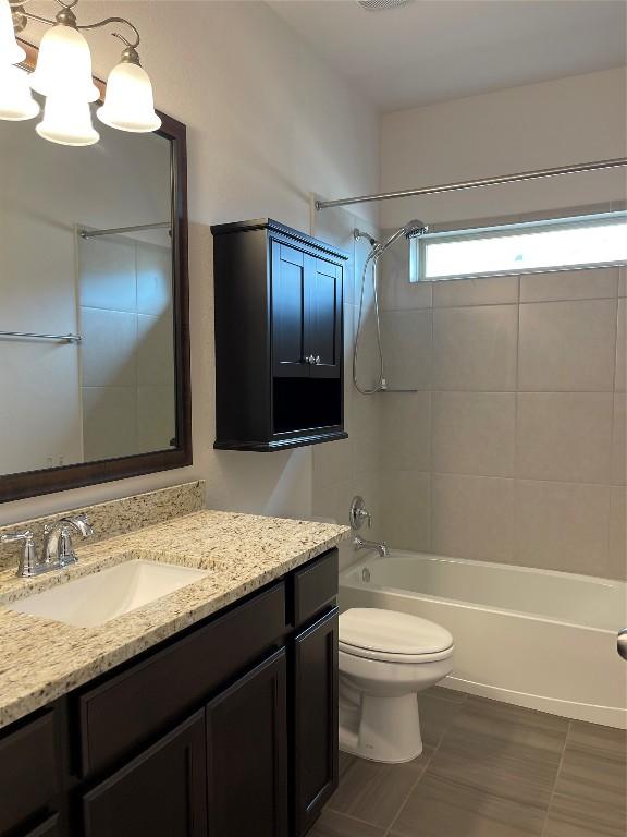 full bathroom with tiled shower / bath, vanity, toilet, and a chandelier