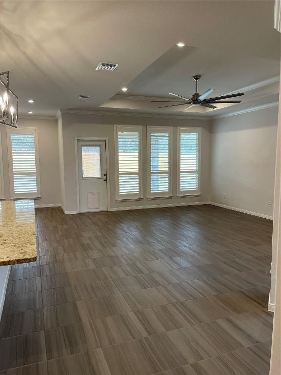 interior space with a raised ceiling, crown molding, and ceiling fan