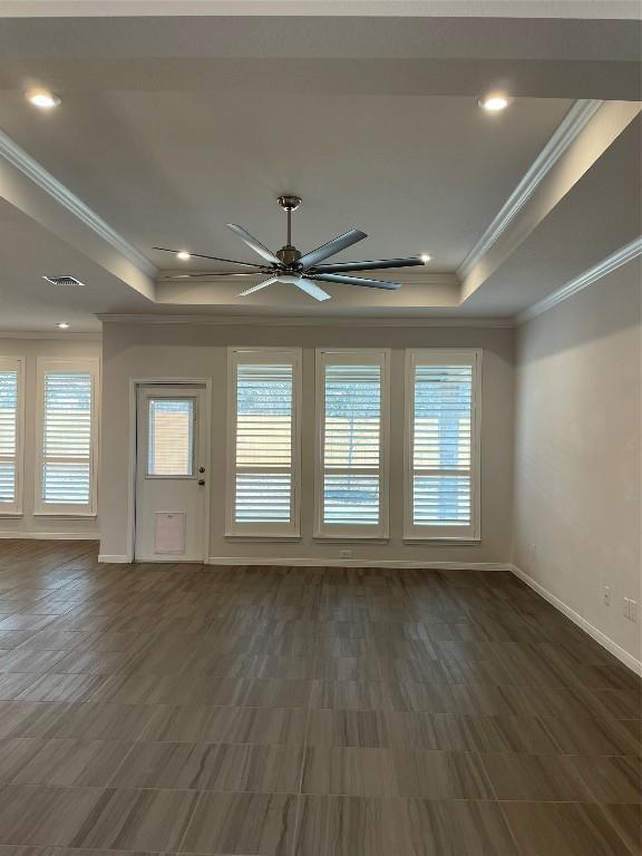 spare room with crown molding, dark hardwood / wood-style floors, ceiling fan, and a tray ceiling