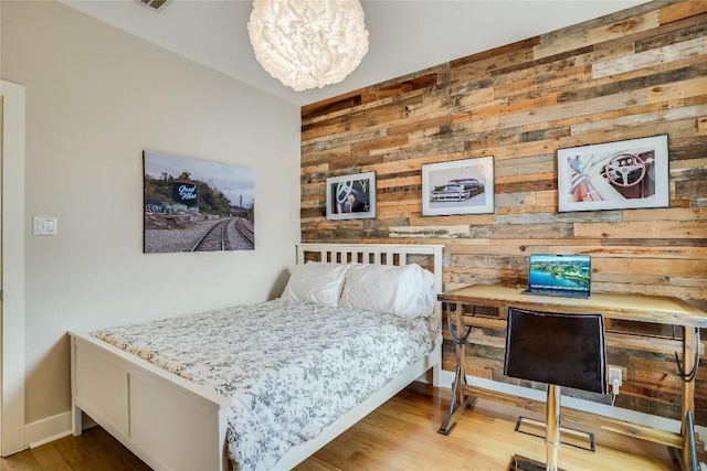 1109 Holly St Unit B, Austin, TX 78702 - bedroom featuring wooden walls, wood finished floors, a chandelier, and baseboards