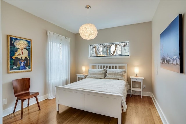 1109 Holly St Unit B, Austin, TX 78702 - bedroom with light wood-type flooring, baseboards, and a chandelier
