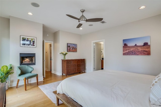 1109 Holly St Unit B, Austin, TX 78702 - bedroom featuring light wood-style flooring, ceiling fan, a glass covered fireplace, baseboards, and recessed lighting