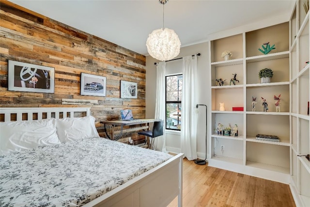 1109 Holly St Unit B, Austin, TX 78702 - bedroom featuring wooden walls, light wood-style flooring, a chandelier, and an accent wall