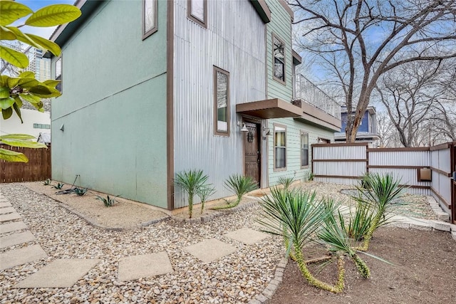 view of side of home featuring fence and a balcony