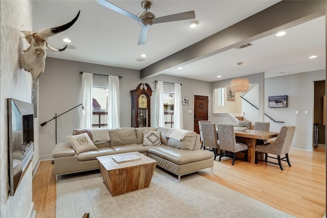 living room featuring ceiling fan, beam ceiling, and light hardwood / wood-style floors