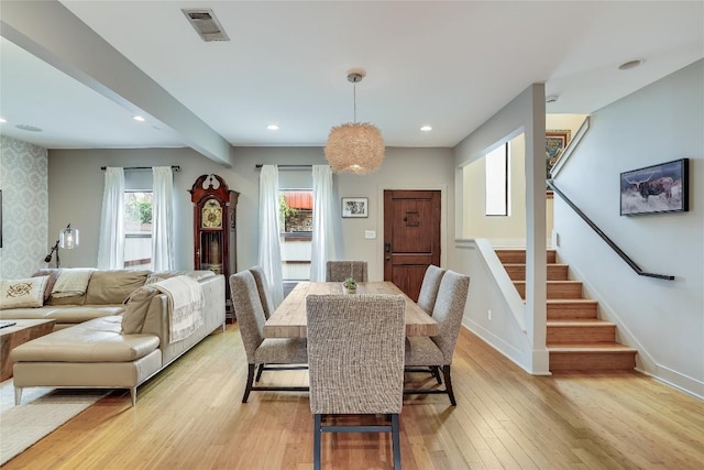 dining room with beamed ceiling and light hardwood / wood-style flooring