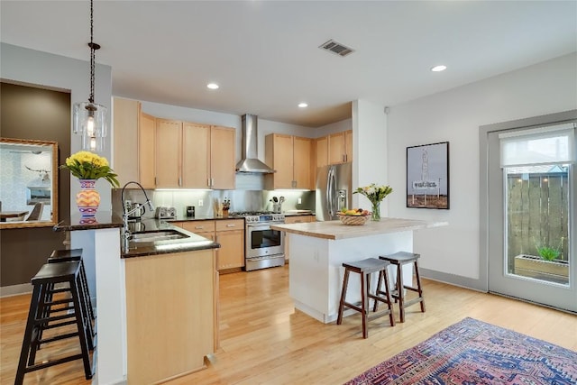 1109 Holly St Unit B, Austin, TX 78702 - kitchen with appliances with stainless steel finishes, light brown cabinetry, wall chimney exhaust hood, a kitchen bar, and a sink
