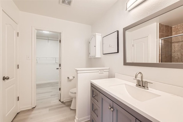 full bath featuring visible vents, toilet, wood finished floors, a spacious closet, and vanity