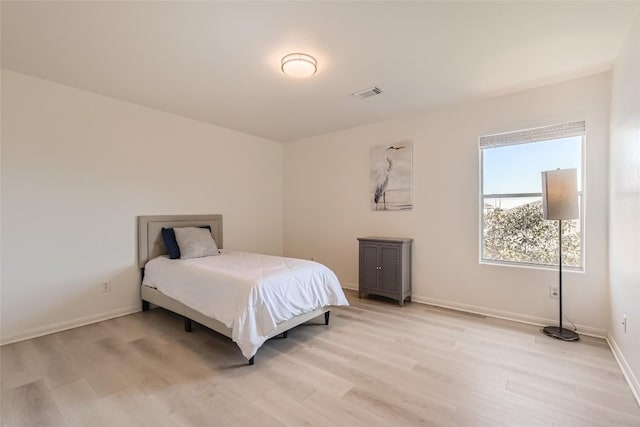 bedroom featuring visible vents, light wood-style flooring, and baseboards