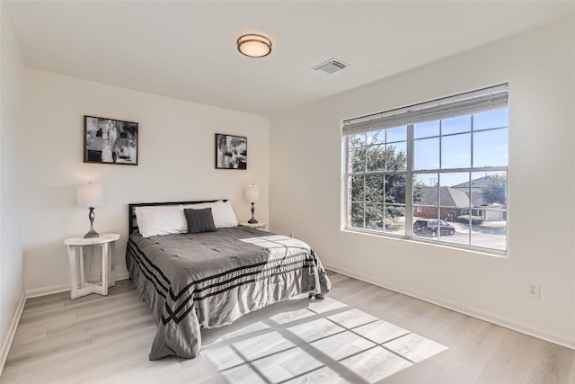 bedroom featuring light wood-style flooring, visible vents, and baseboards