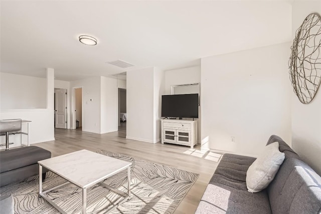 living room featuring visible vents, baseboards, and wood finished floors