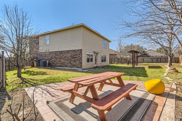 rear view of house with brick siding, a lawn, a fenced backyard, a patio area, and outdoor dining space