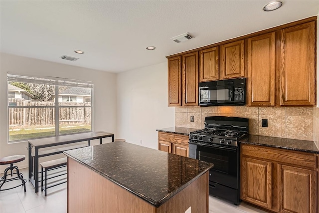 kitchen with black appliances, visible vents, brown cabinets, and a center island