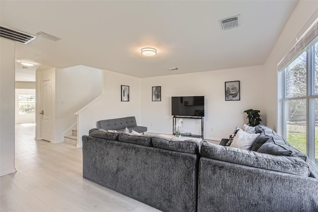 living area with visible vents, baseboards, light wood-style flooring, and stairs