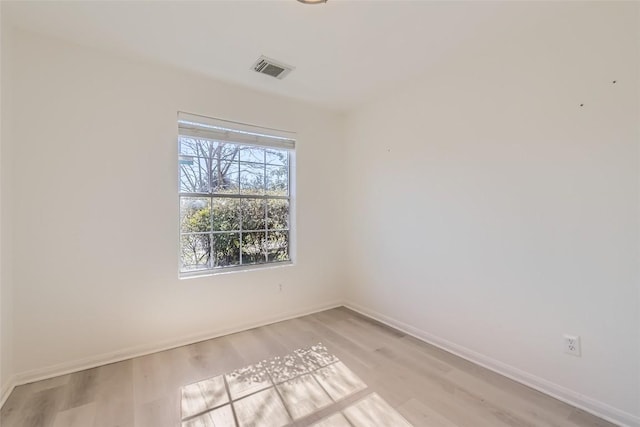 spare room featuring light wood-type flooring, visible vents, and baseboards