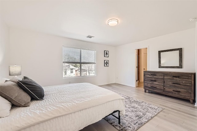 bedroom featuring baseboards, visible vents, and light wood finished floors