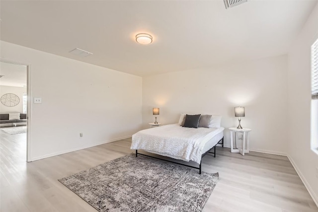 bedroom with visible vents, light wood-style flooring, and baseboards