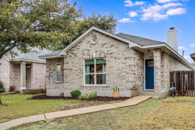 ranch-style house featuring a front yard, brick siding, fence, and a chimney