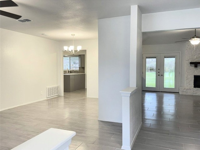 12104 Sage Hen Cir, Austin, TX 78727 - unfurnished living room featuring ceiling fan, a chandelier, wood finished floors, and a stone fireplace