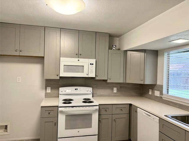 12104 Sage Hen Cir, Austin, TX 78727 - kitchen with white appliances, gray cabinetry, light countertops, tasteful backsplash, and a textured ceiling