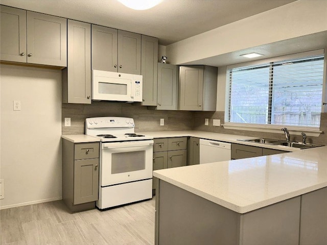 12104 Sage Hen Cir, Austin, TX 78727 - kitchen featuring white appliances, gray cabinetry, decorative backsplash, a peninsula, and light wood-type flooring