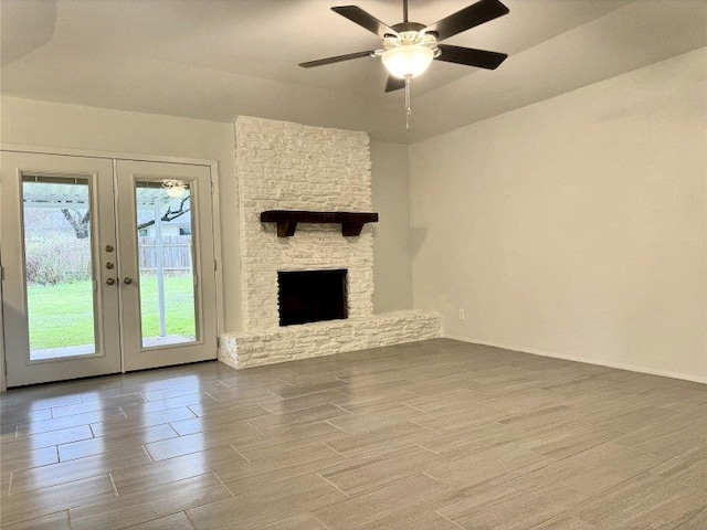 12104 Sage Hen Cir, Austin, TX 78727 - unfurnished living room with french doors, wood tiled floors, a ceiling fan, and a stone fireplace