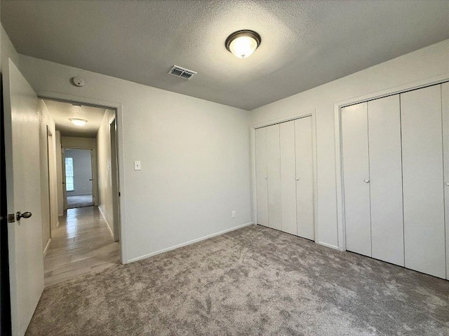 12104 Sage Hen Cir, Austin, TX 78727 - unfurnished bedroom featuring multiple closets, carpet flooring, and a textured ceiling