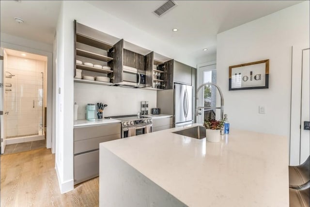 111 Little Walnut Dr Unit 1, Austin, TX 78753 - kitchen featuring open shelves, appliances with stainless steel finishes, light wood-style floors, light countertops, and gray cabinets