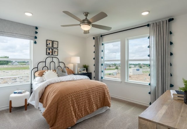 bedroom featuring light carpet, multiple windows, and ceiling fan