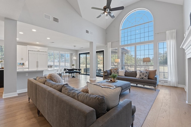 living room with ceiling fan, high vaulted ceiling, and light hardwood / wood-style flooring