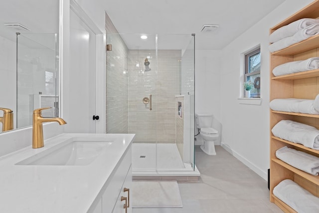 bathroom with a shower with door, vanity, tile patterned floors, and toilet