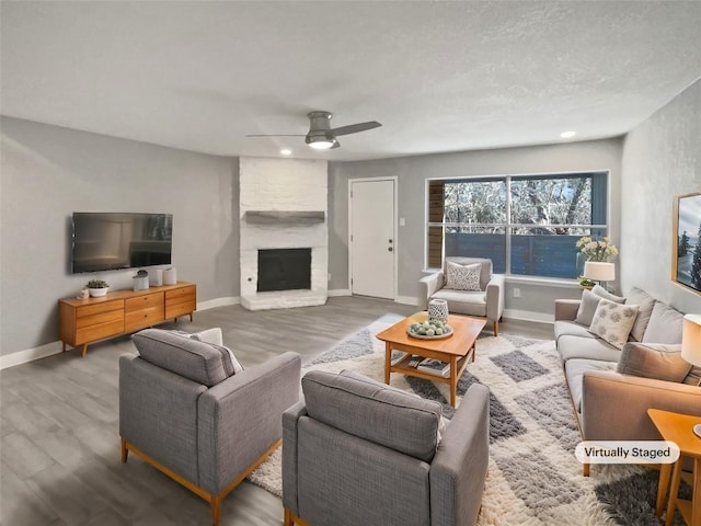 living room featuring a large fireplace, hardwood / wood-style flooring, and ceiling fan