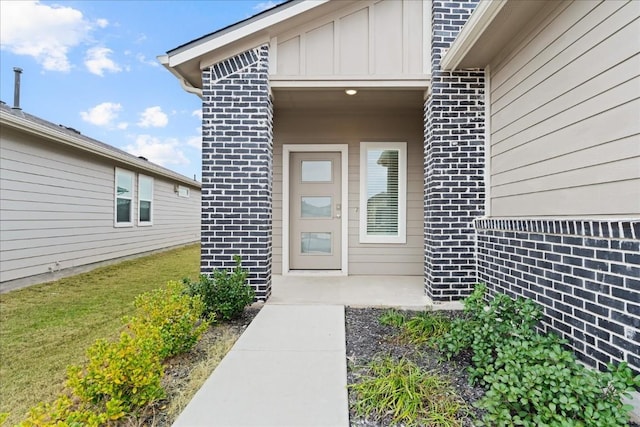 view of exterior entry with brick siding and board and batten siding