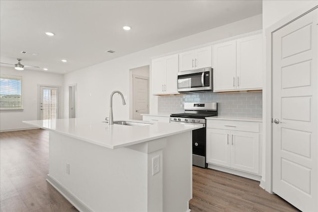 kitchen featuring appliances with stainless steel finishes, sink, a center island with sink, and white cabinets