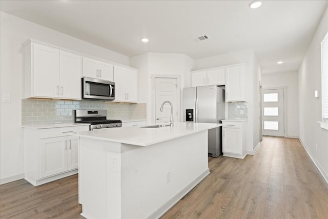 kitchen featuring appliances with stainless steel finishes, sink, a center island with sink, and white cabinets