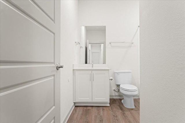 bathroom with wood-type flooring, toilet, and vanity