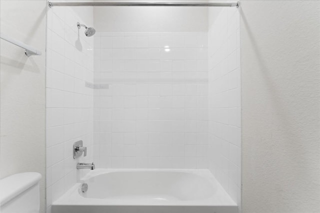 bathroom featuring toilet and tiled shower / bath