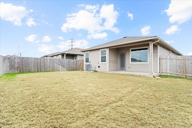 rear view of property with a patio, a yard, and central AC